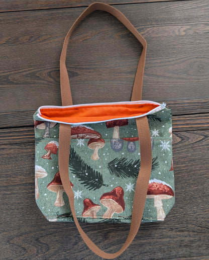 Crafted from durable cotton, this 13x9" bag features a sturdy 3.5" flat bottom and comfortable 26-inch straps for easy carrying. The vibrant orange lining adds a pop of color inside, while two outer pockets and one inner pocket keep your essentials organized. 