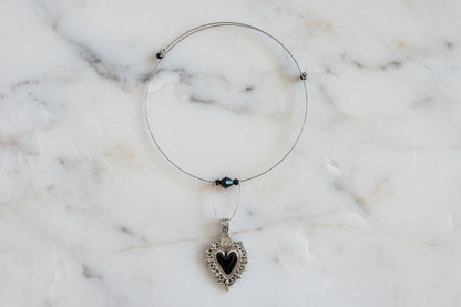 This elegant memory wire choker combines timeless style with modern sophistication. Featuring a striking black stainless steel heart pendant accented with lustrous black beads, it adjusts perfectly to fit neck sizes 4 to 4.5 inches. The durable .025" wire construction ensures lasting wear without losing its shape, while the lightweight design at just 0.28 oz makes it comfortable for all-day elegance. Whether layered with other pieces or worn solo, this versatile choker adds an instant touch of charm to any 