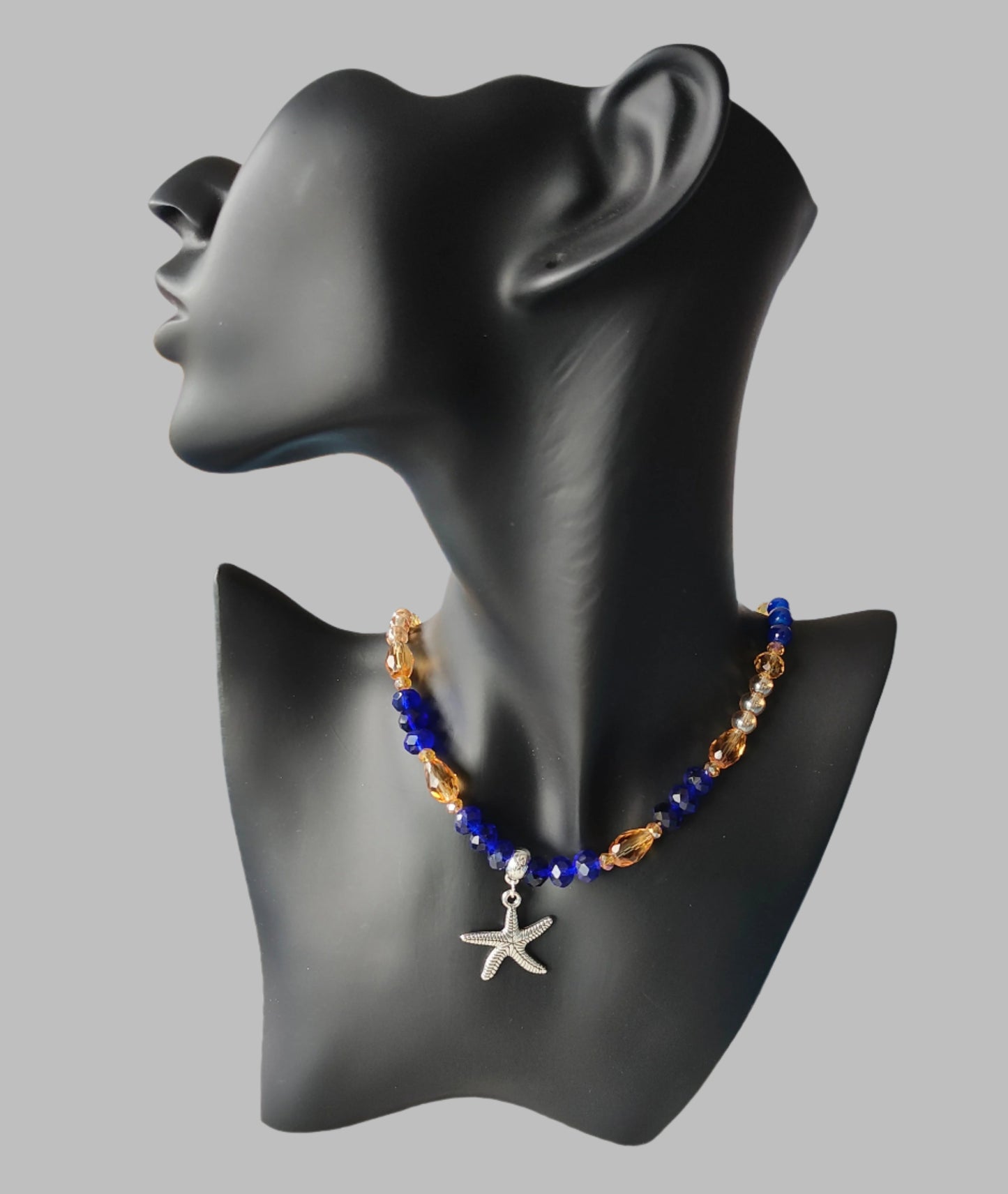 Add a touch of the ocean to your outfit with our Silver Starfish Necklace. Featuring a delicate silver starfish charm adorned with blue and gold crystal and glass beads, this necklace is perfect for any occasion. Choose between 16 and 18 inches for the perfect fit, and enjoy its lightweight design at only 0.72 oz.

Necklace - Silver starfish charm with blue and gold crystal and glass beads