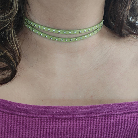Elevate your style with our stunning Necklace - Choker! Made from 5mm studded olive green faux suede cord, it's a versatile piece that adds a touch of glam to any outfit. The perfect accessory for any fashion-forward individual looking to make a statement.