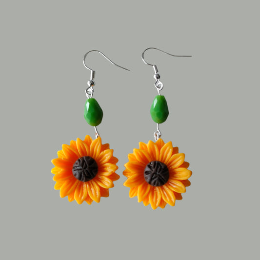 Add a touch of sunshine to any outfit with our Sunflower Earrings! Featuring a vibrant green bead and a playful sunflower design on a silver hook, these earrings are sure to make a statement. At 2.25 inches long and weighing only 0.27 ounces, they are lightweight and comfortable to wear all day. (Flower power never felt so good!)