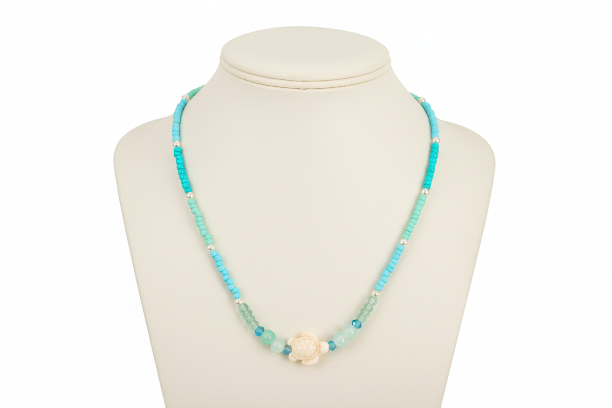 Necklace with turquoise beads and an accent turtle bead on a mannequin bust against a white background