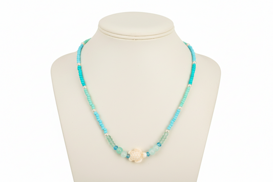 Necklace with turquoise beads and an accent turtle bead on a mannequin bust against a white background