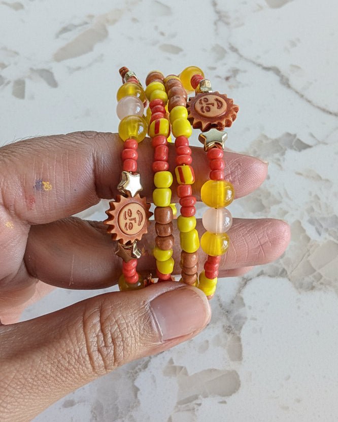 This vibrant memory wire bracelet features four coils adorned with yellow and sun beads, complemented by yellow, tan, and orange spacer beads. Its flexible design ensures a comfortable fit for any wrist size, making it an eye-catching accessory that brightens your look with warm, sunny hues. Perfect for adding a splash of color and effortless style to your everyday outfits.