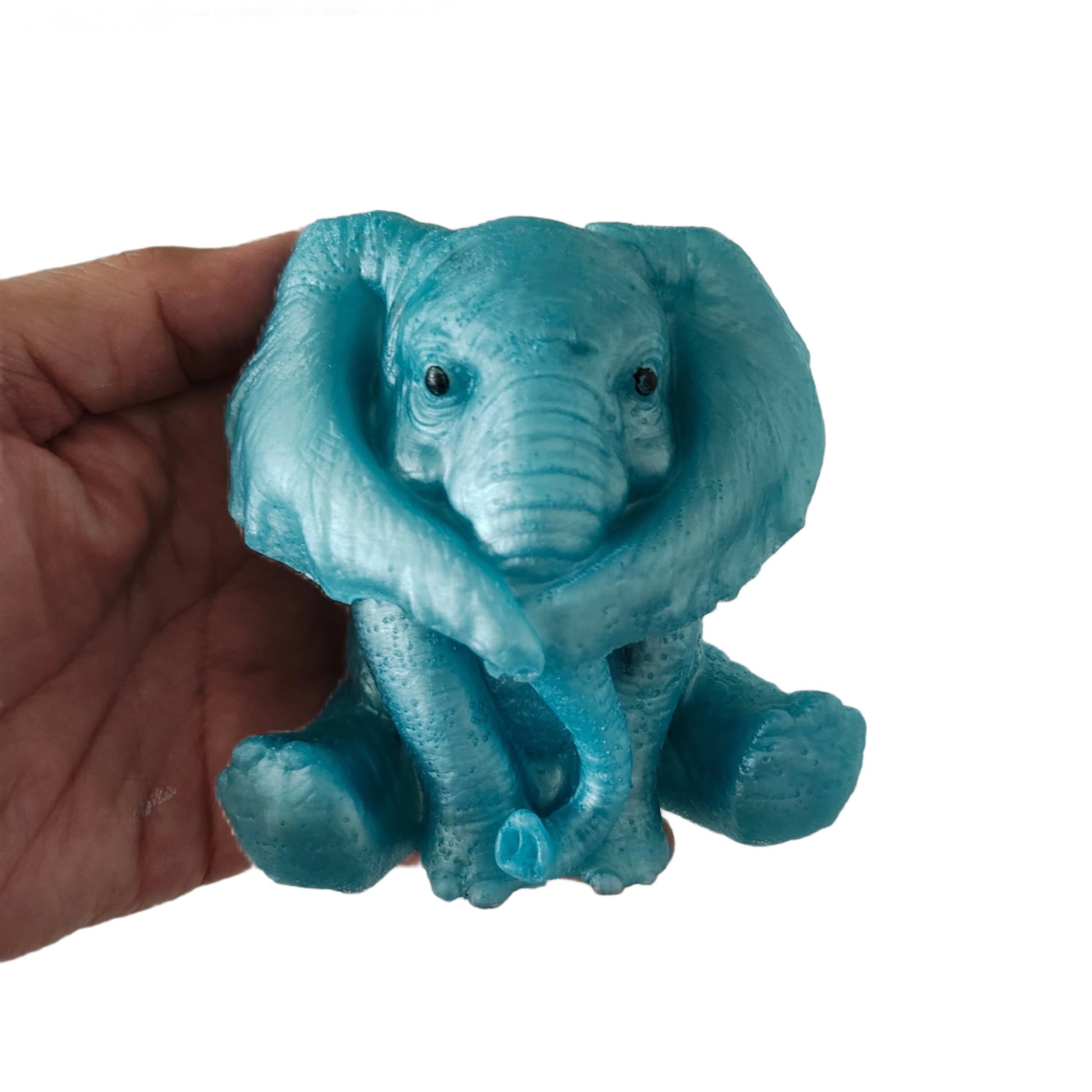 Blue elephant figurine held in a hand against a white background