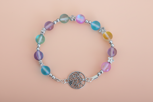 Multicolored beaded bracelet with a silver tree of life charm on a beige background