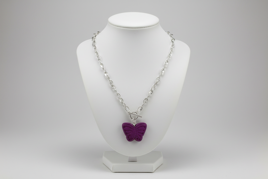 Necklace with a purple butterfly pendant on a white bust against a gray background
