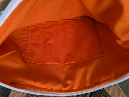 Snowy Mushrooms bag with orange lining two outer pockets one inner pocket and a zipper closure