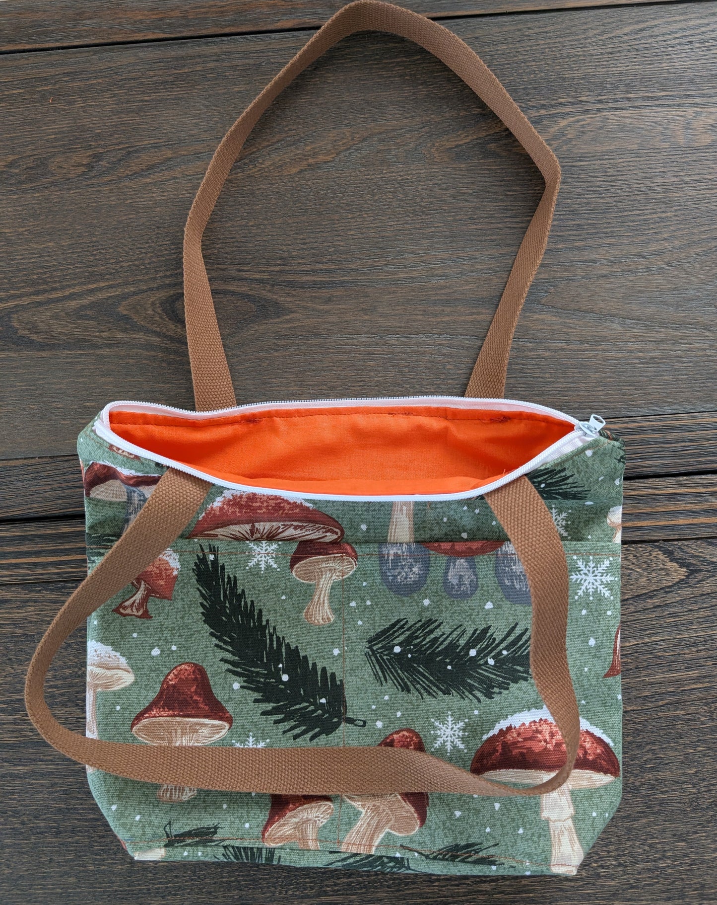 Snowy Mushrooms bag with orange lining two outer pockets one inner pocket and a zipper closure