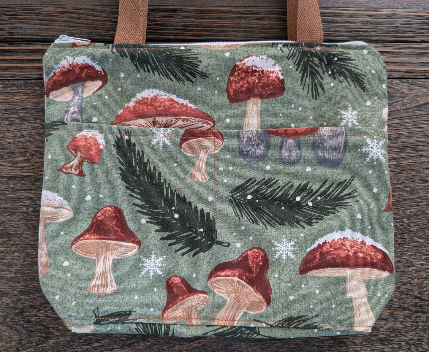 Snowy Mushrooms bag with orange lining two outer pockets one inner pocket and a zipper closure