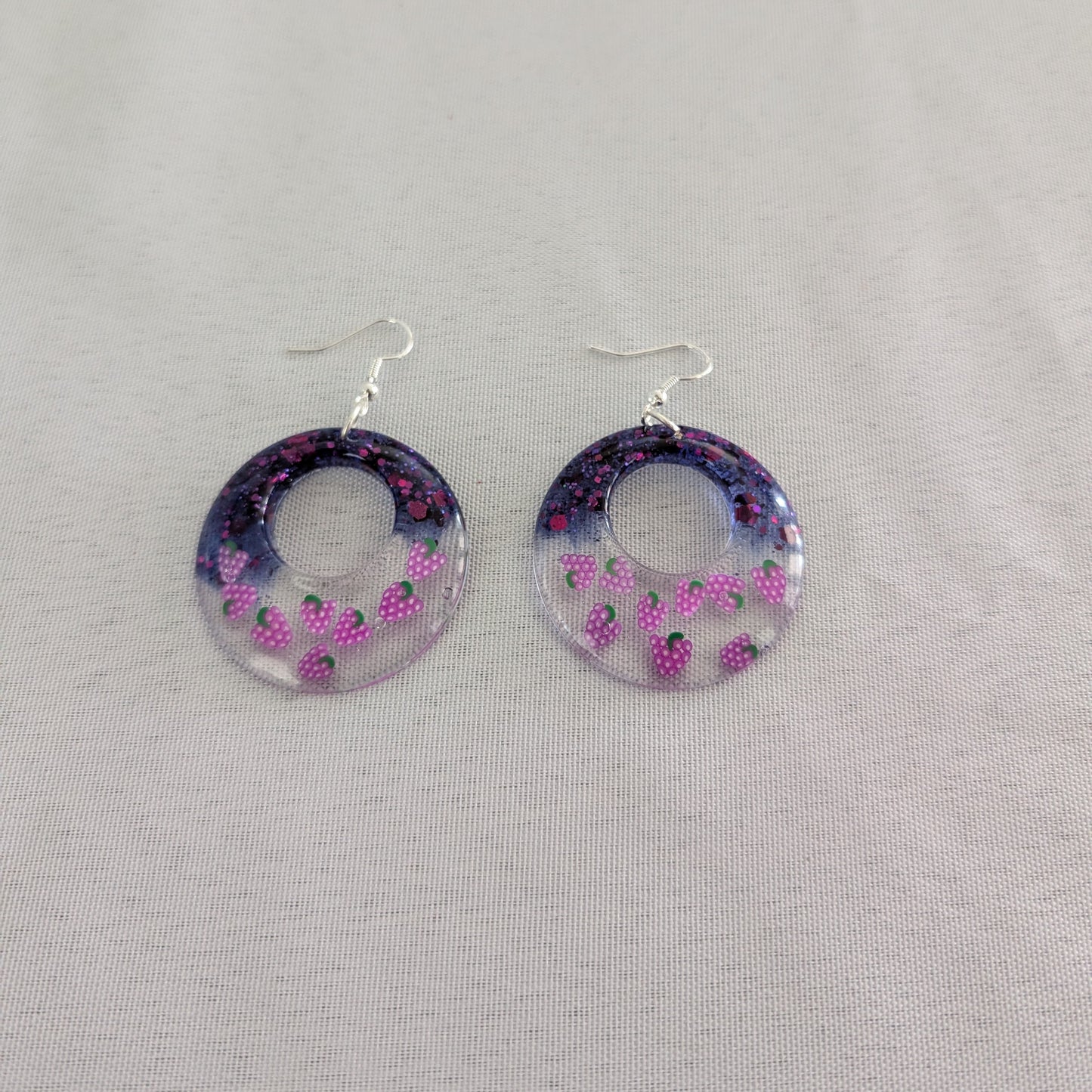 Hoop earrings with grapes design on a gray background
