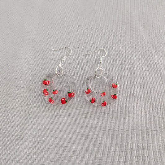 Hoop earrings with red apple accents on a gray background