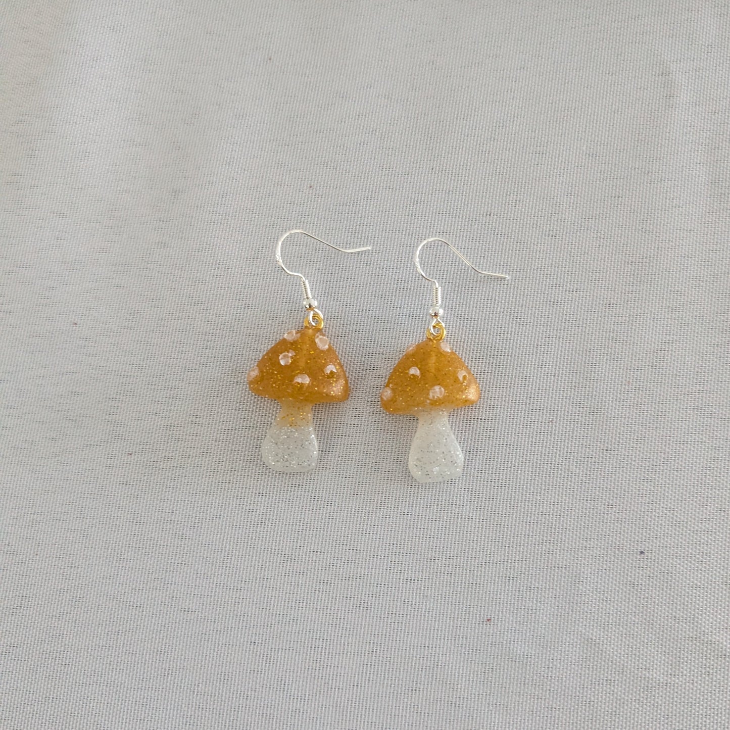 Mushroom-shaped earrings on a light gray background