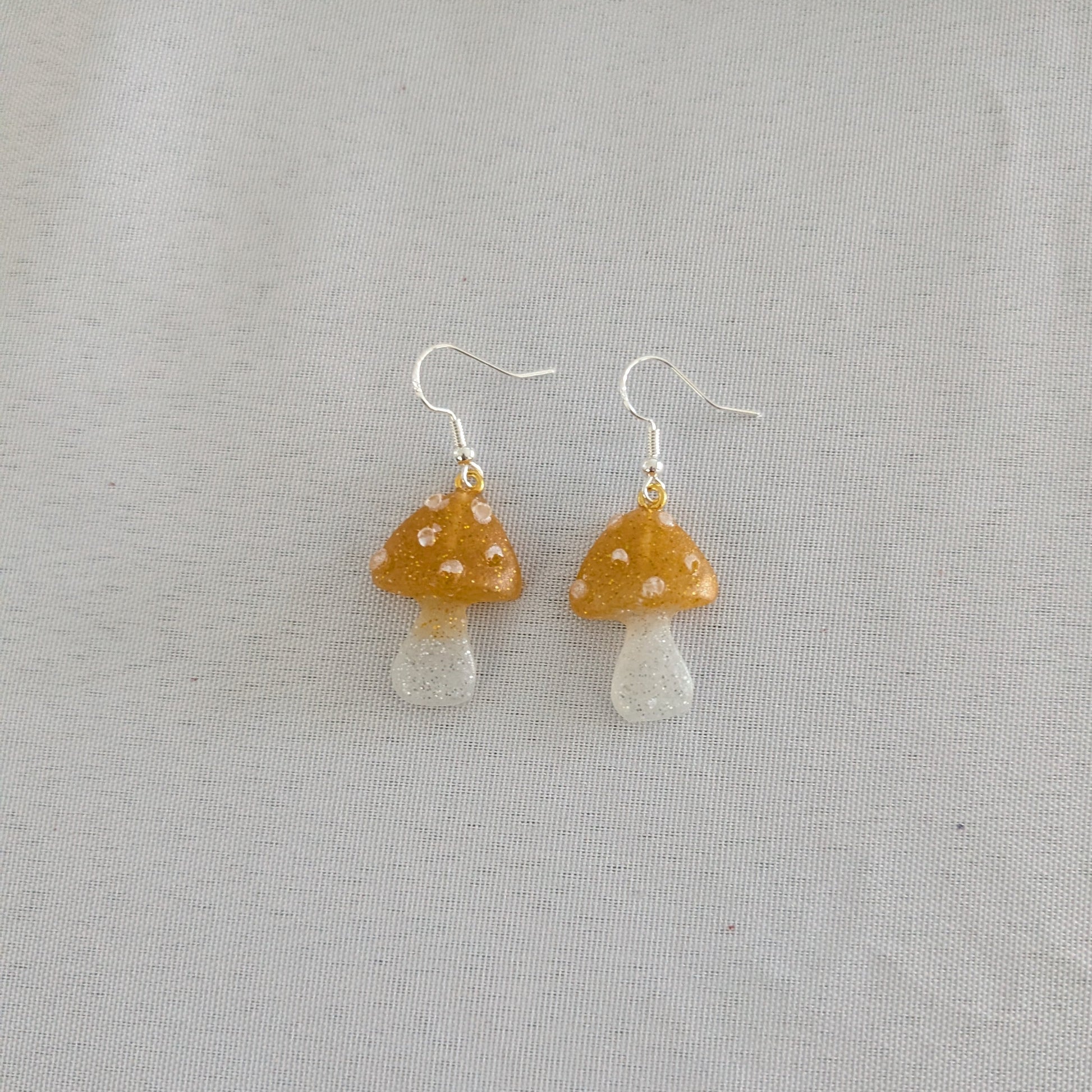 Mushroom-shaped earrings on a light gray background