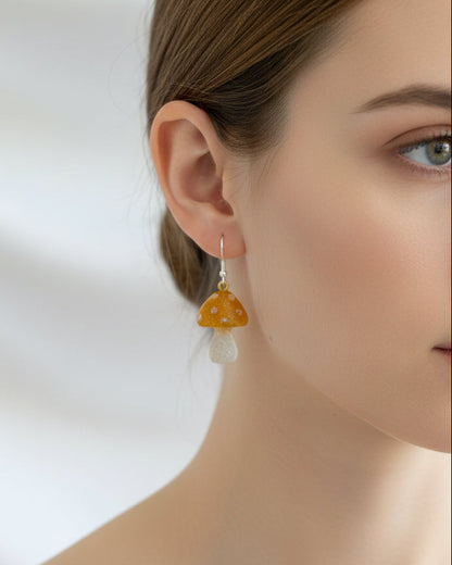 Close-up of a person wearing a pair of mushroom earrings with a white background