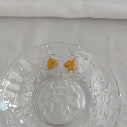 God mushroom-shaped earrings on a decorative glass plate with a white background