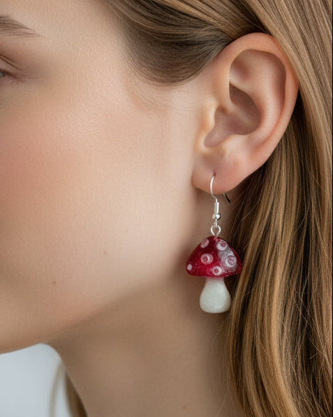 Red and white mushroom-shaped earrings worn by a person