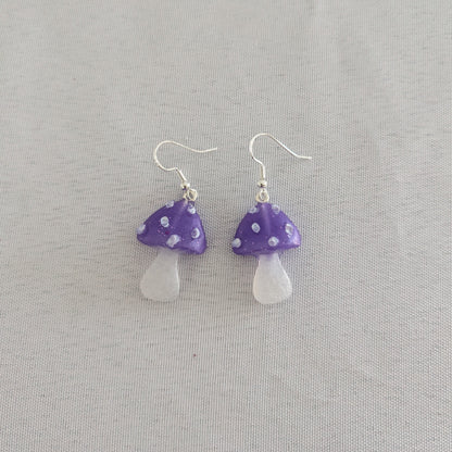 Mushroom-shaped earrings with purple caps and white bases on a gray background