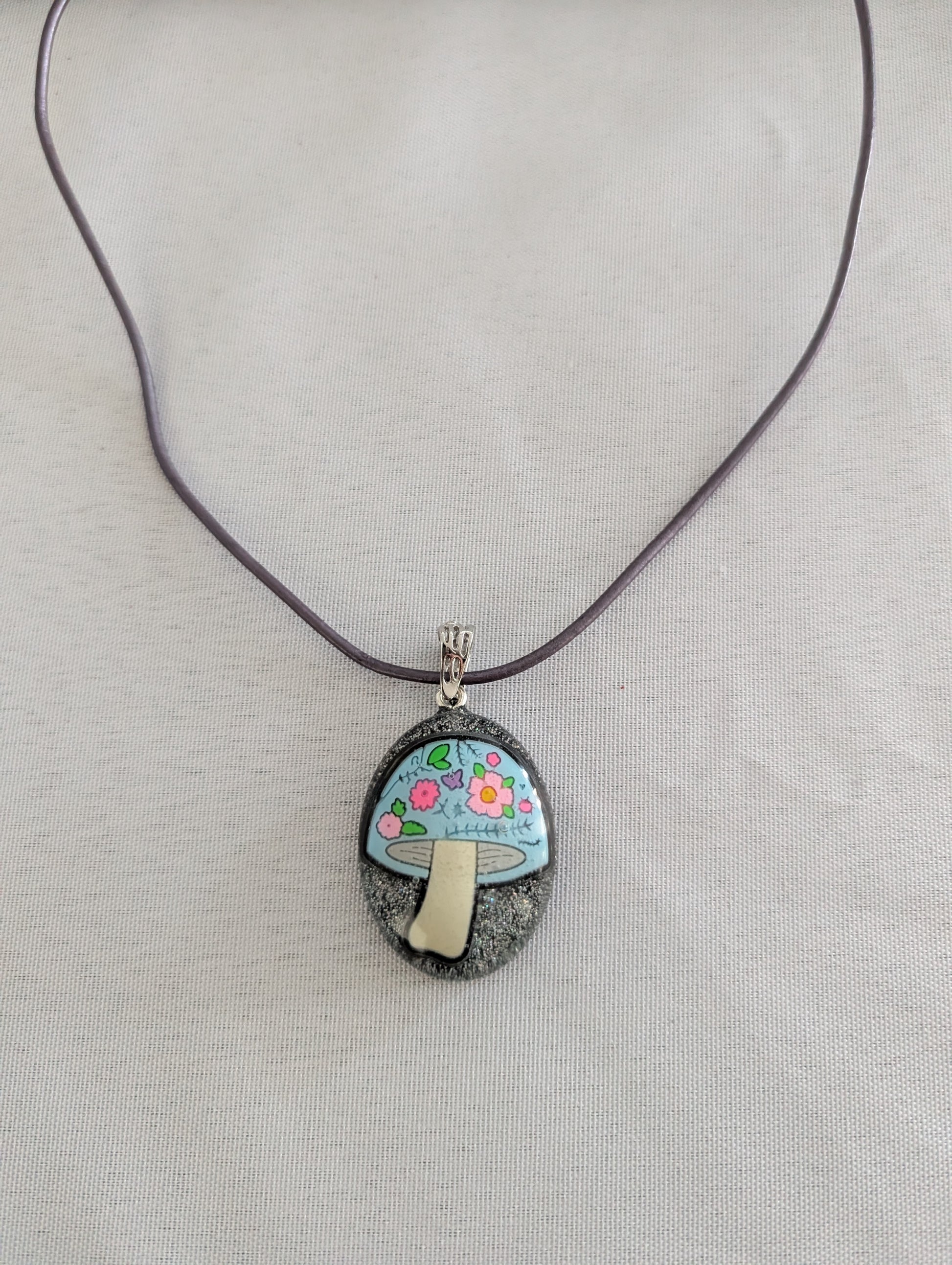 Necklace with a pendant featuring a mushroom floral design on a plain background