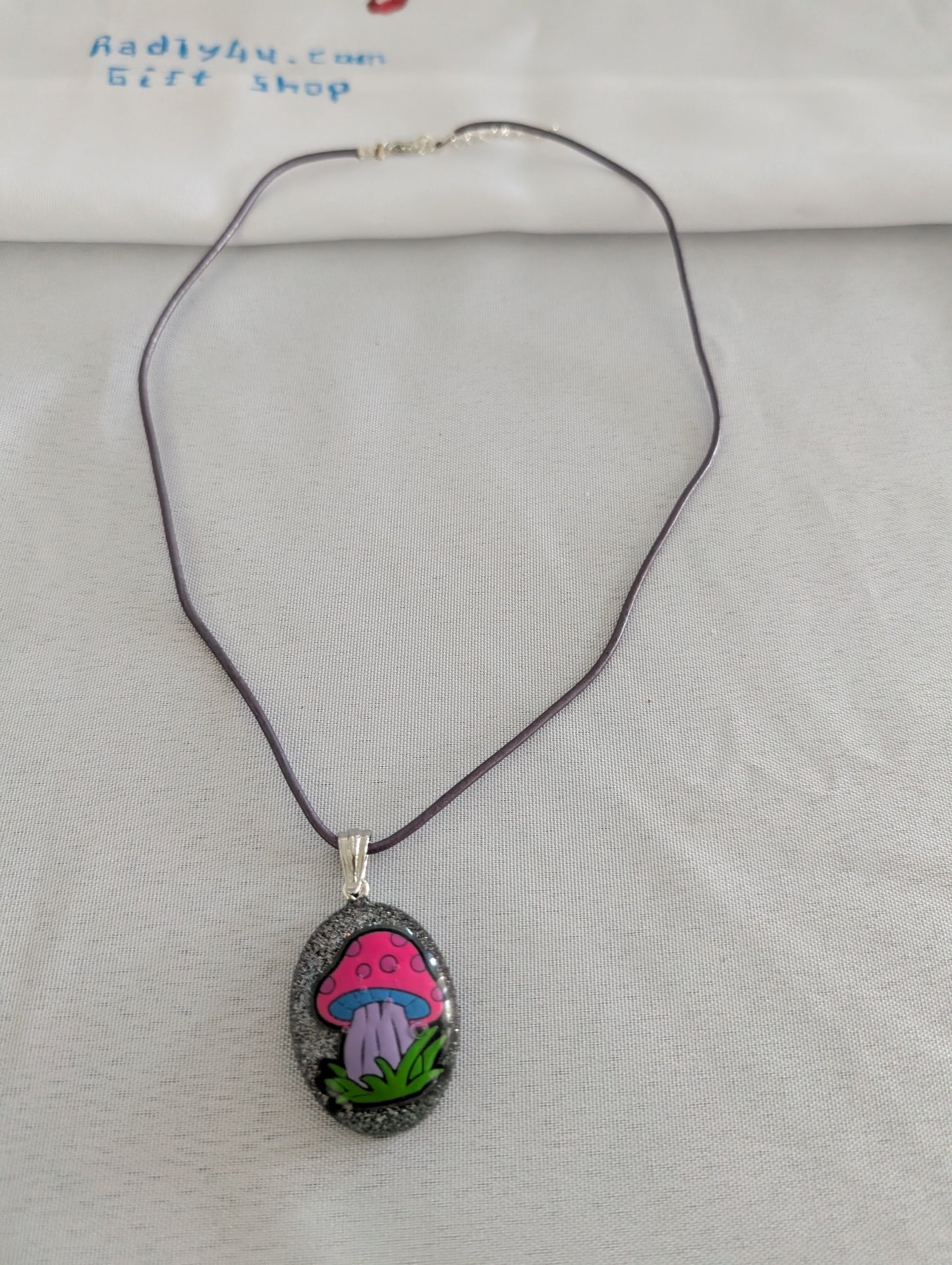 Necklace with a pendant featuring a pink mushroom design on a light gray background.