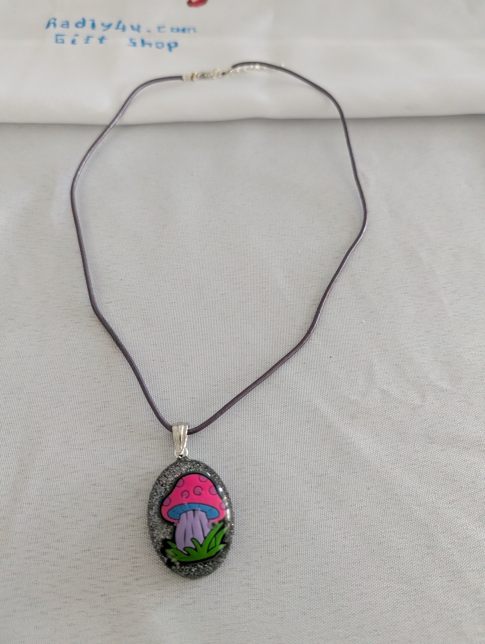 Necklace with a pendant featuring a pink mushroom design on a light gray background.