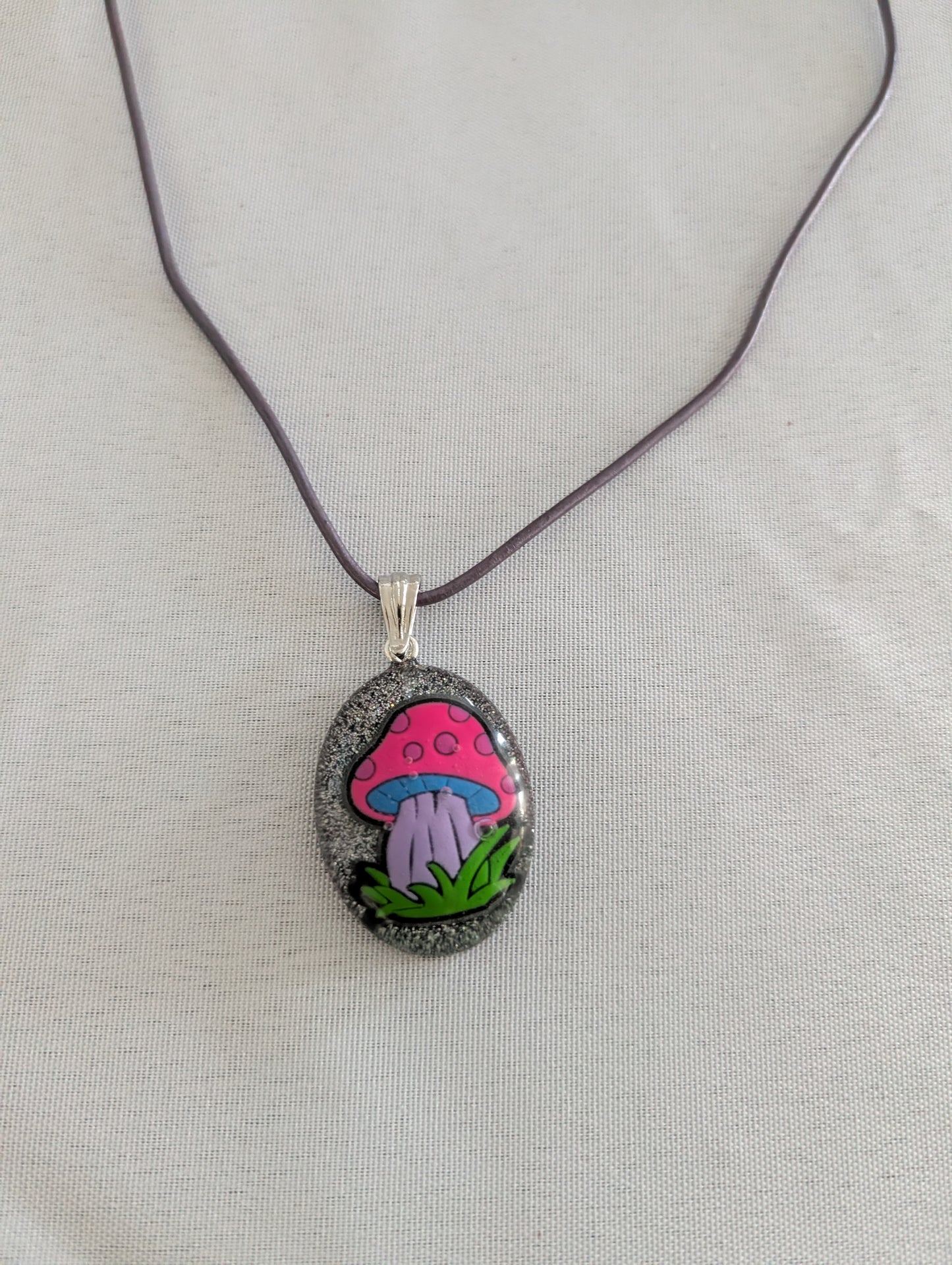 Necklace with a pendant featuring a pink mushroom design on a gray background