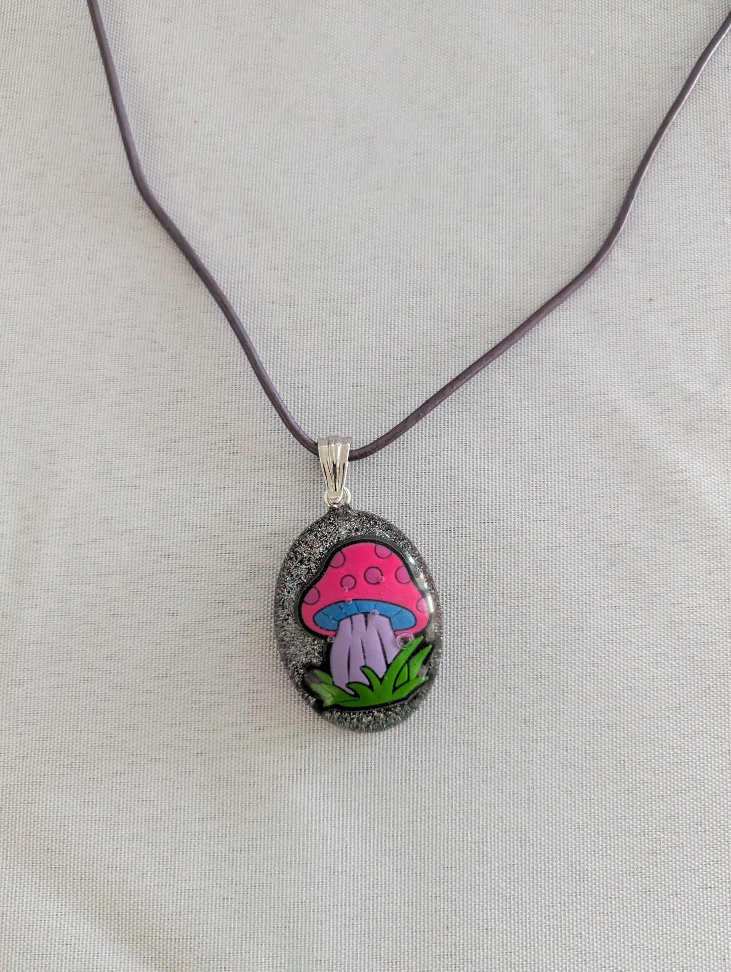 Necklace with a pendant featuring a colorful mushroom design on a light gray background
