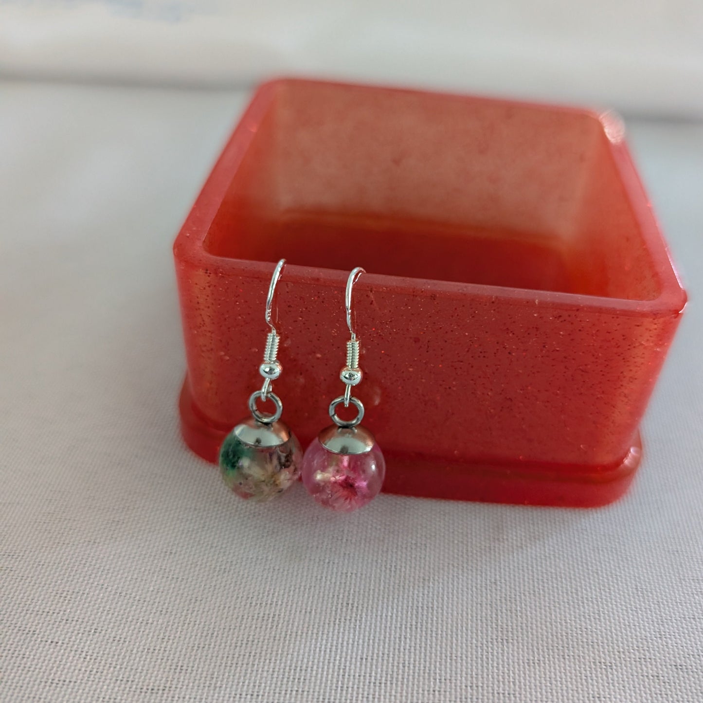 Pair of earrings with colorful beads in a red box on a light background