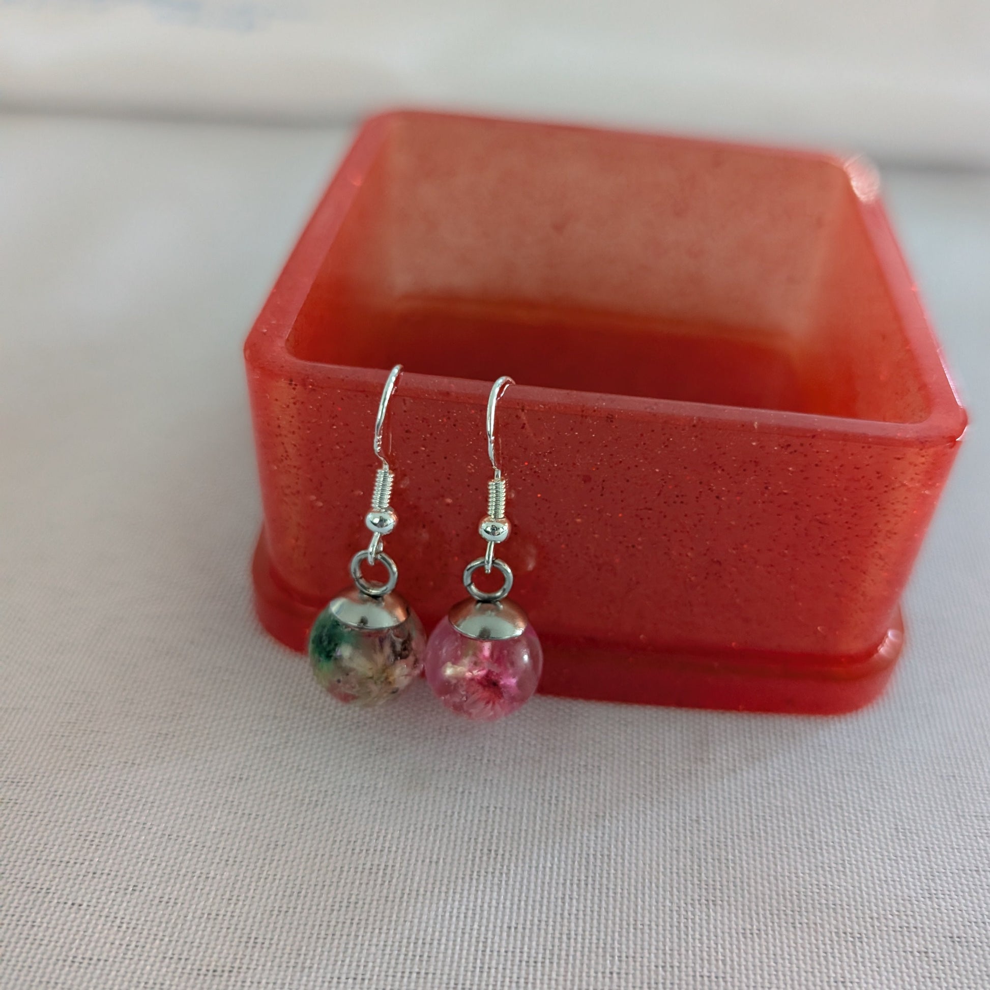 Pair of earrings with colorful beads in a red box on a light background