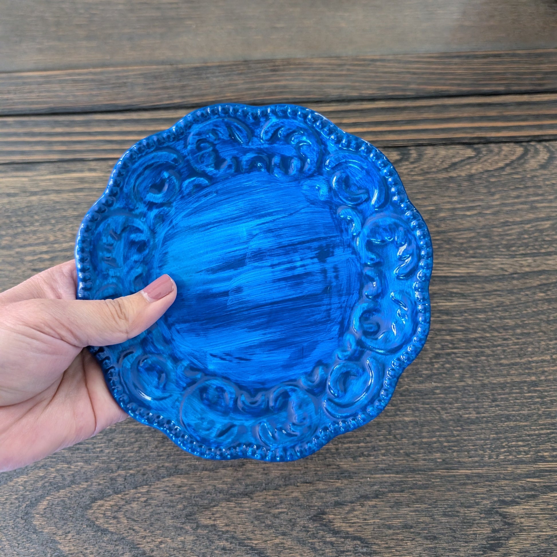 Blue decorative plate held by a hand on a wooden surface