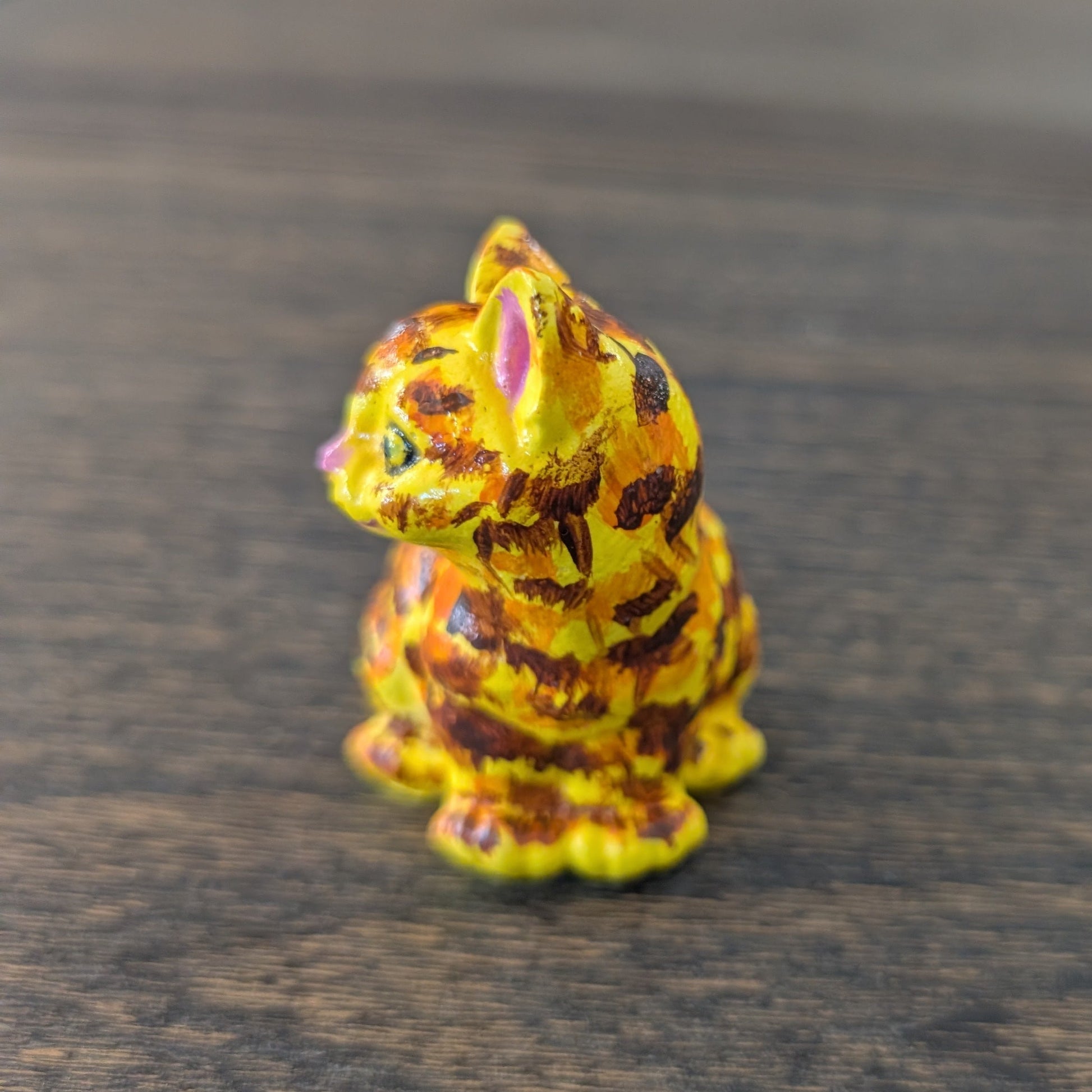 Small figurine of a cat with a colorful pattern on a wooden surface