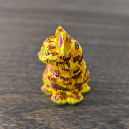 Small figurine of a cat with a colorful pattern on a wooden surface