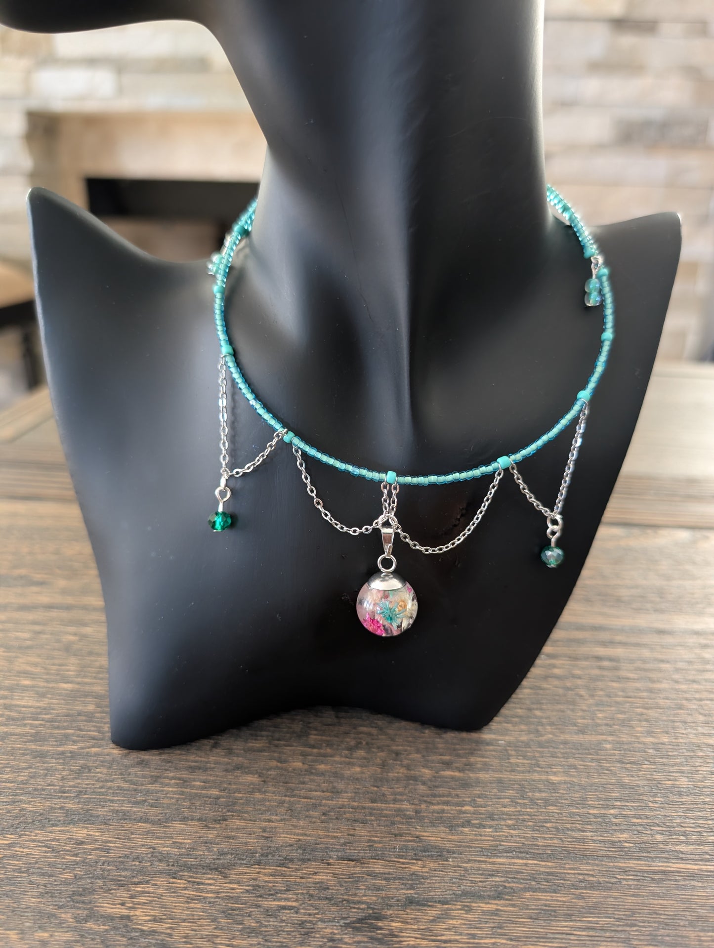 Necklace with colorful pendant on a black mannequin bust against a wooden background