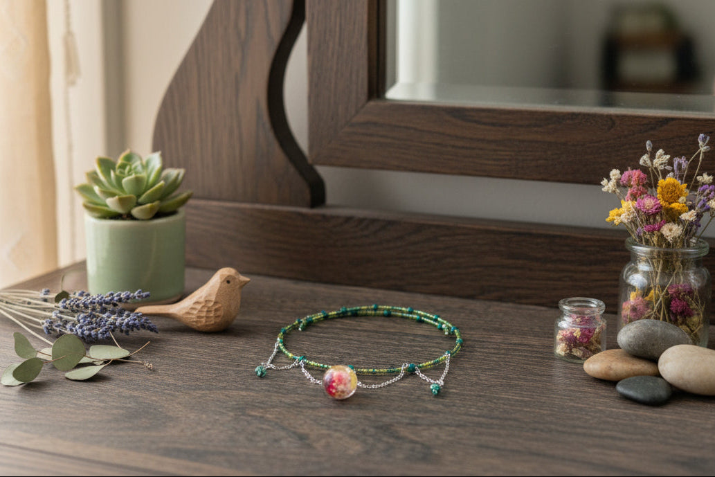 Necklace on a wooden surface with decorative items including a plant, stones, and flowers.