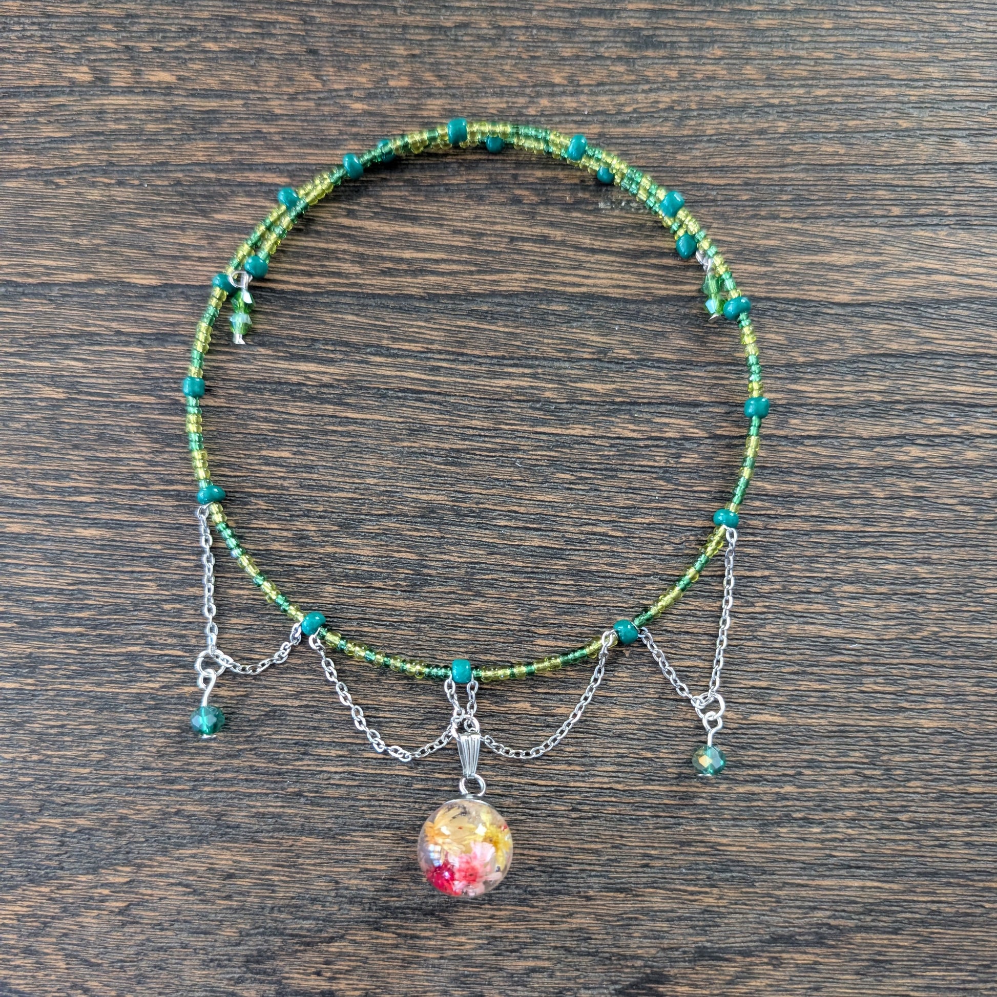 Necklace with colorful beads and a floral bead pendant on a wooden surface