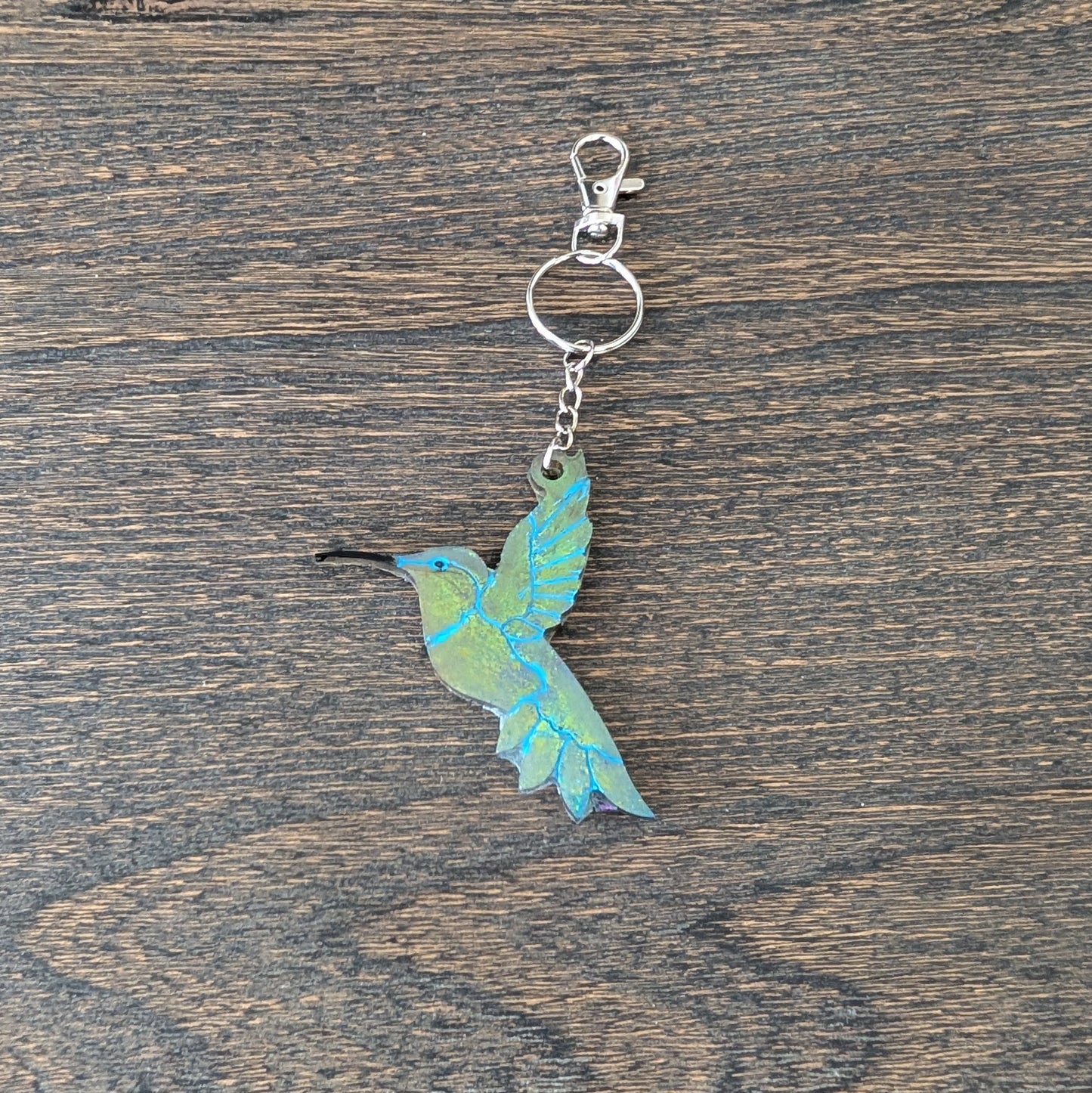 Keychain with a blue and green bird design on a wooden surface