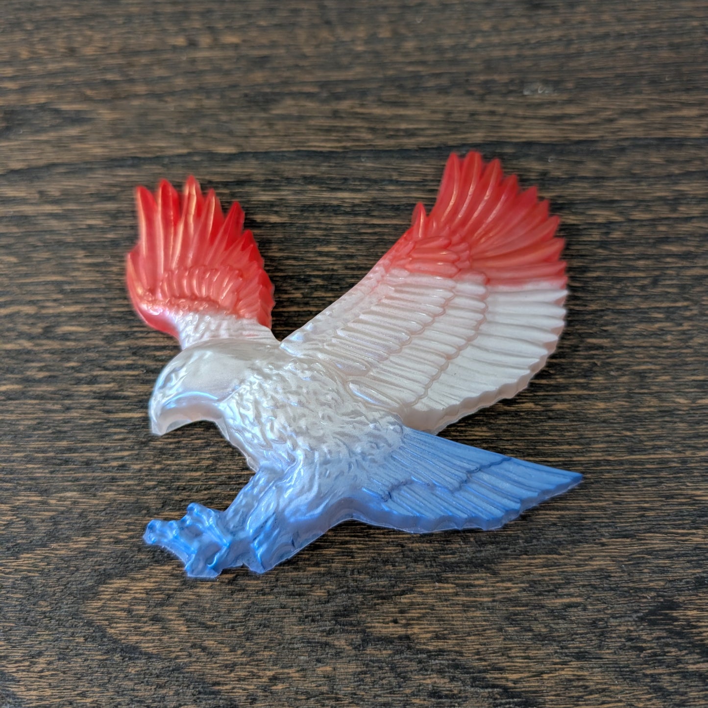 resin eagle with red and blue wings on a wooden surface