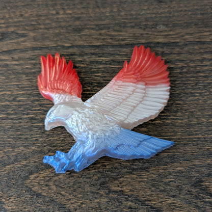 resin eagle with red and blue wings on a wooden surface