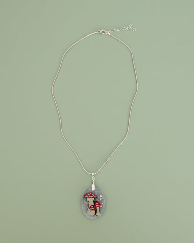 Necklace with a pendant featuring mushrooms on a green background