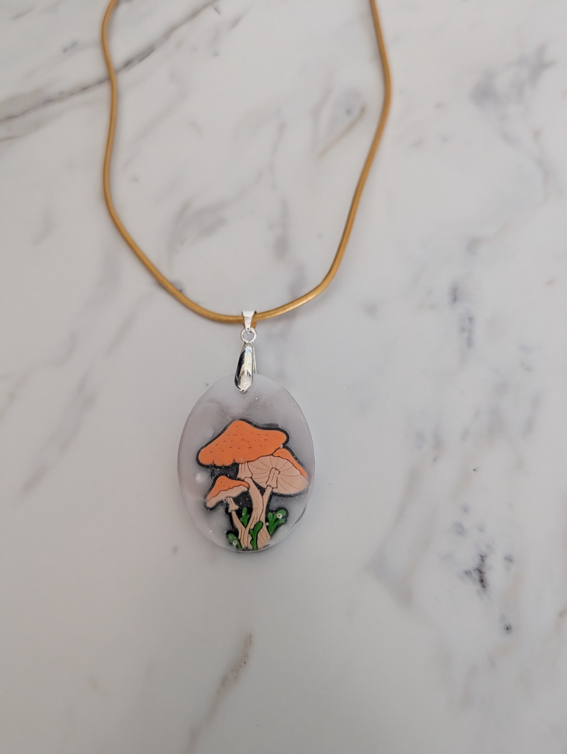 Necklace with a pendant featuring mushroom design on a marble surface