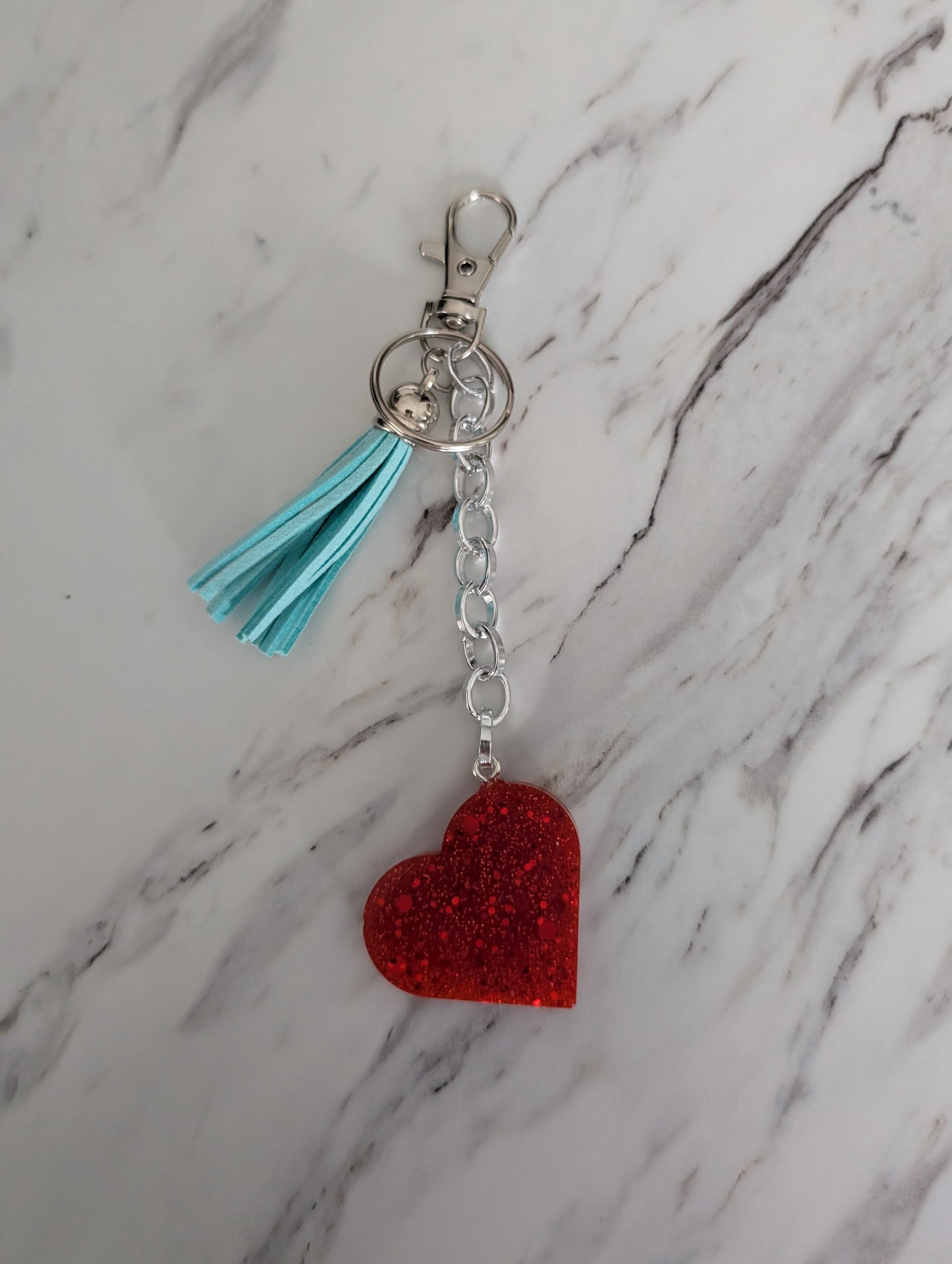 Keychain with red heart and blue tassel on a marble background