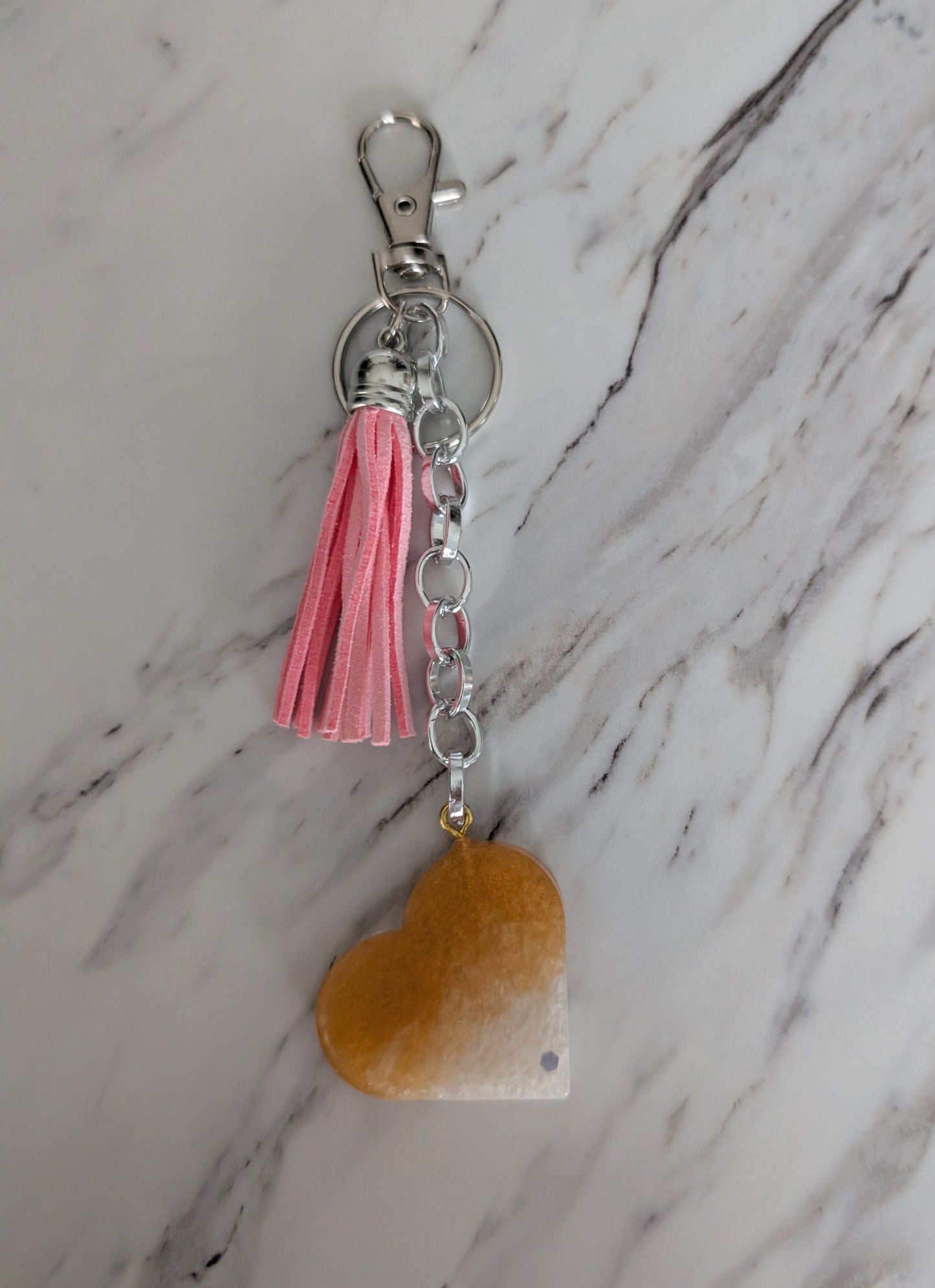 Keychain with pink tassel and heart-shaped charm on a marble background