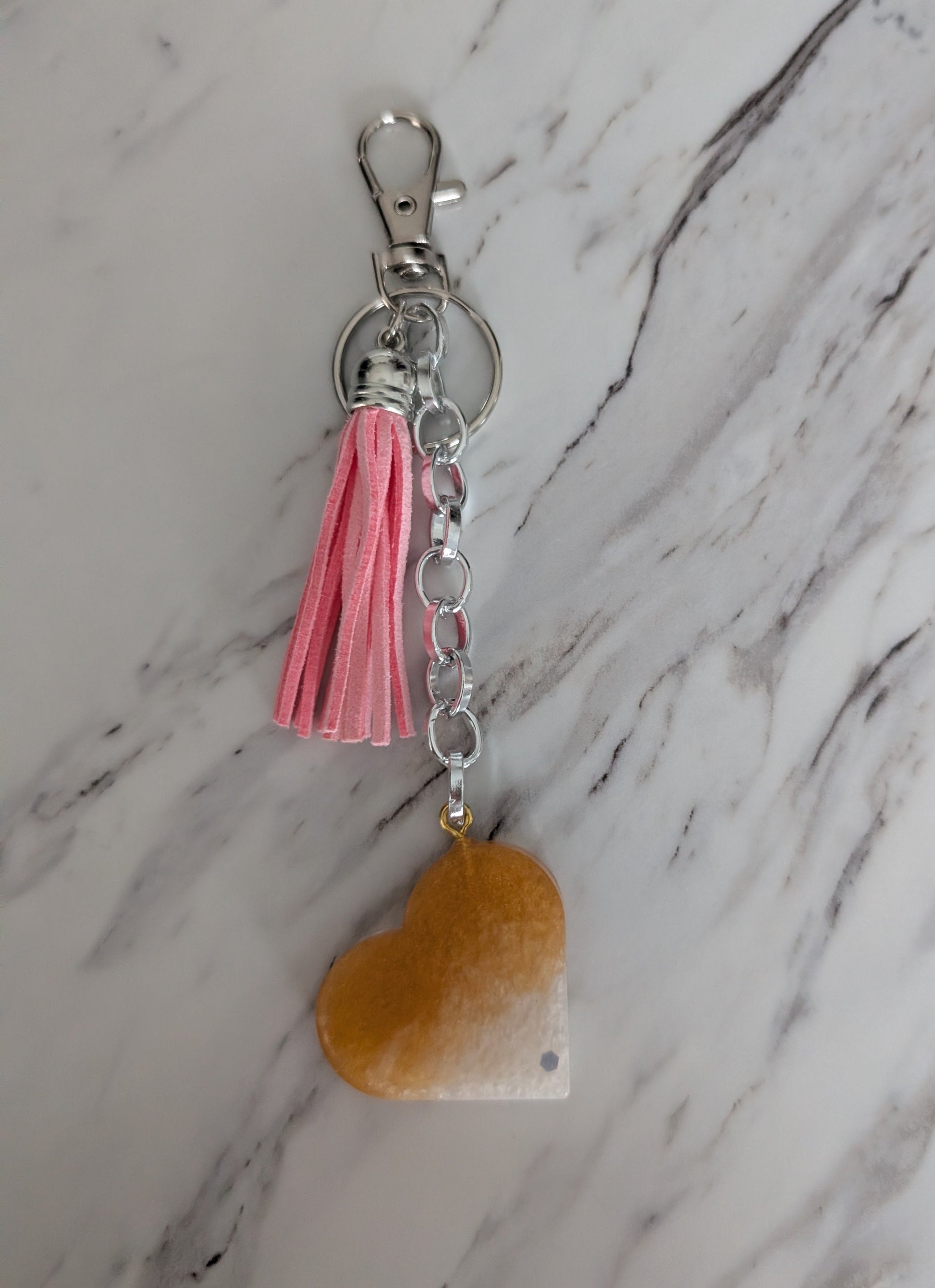 Keychain with pink tassel and heart-shaped charm on a marble background