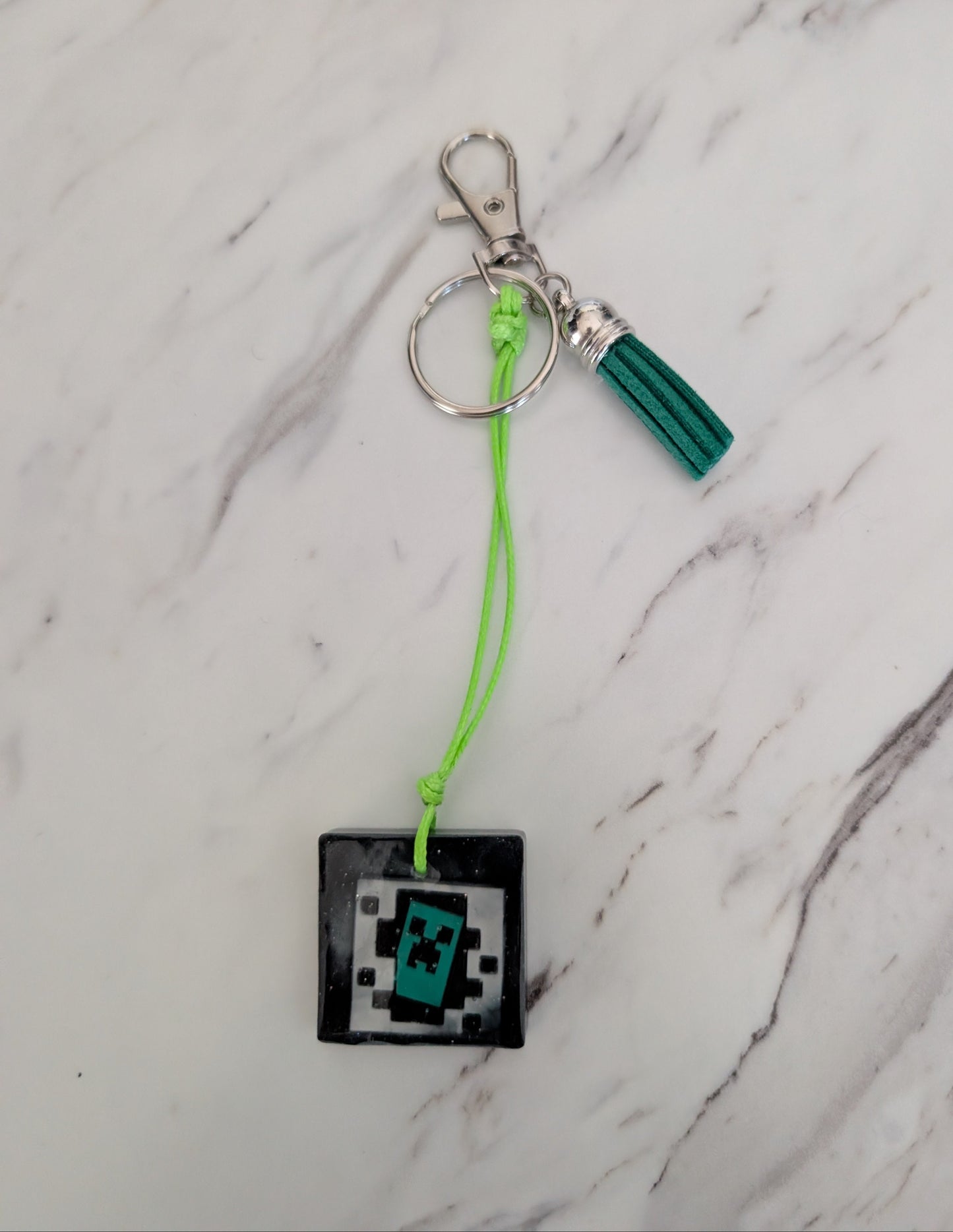 Keychain with a pixelated character charm on a marble surface
