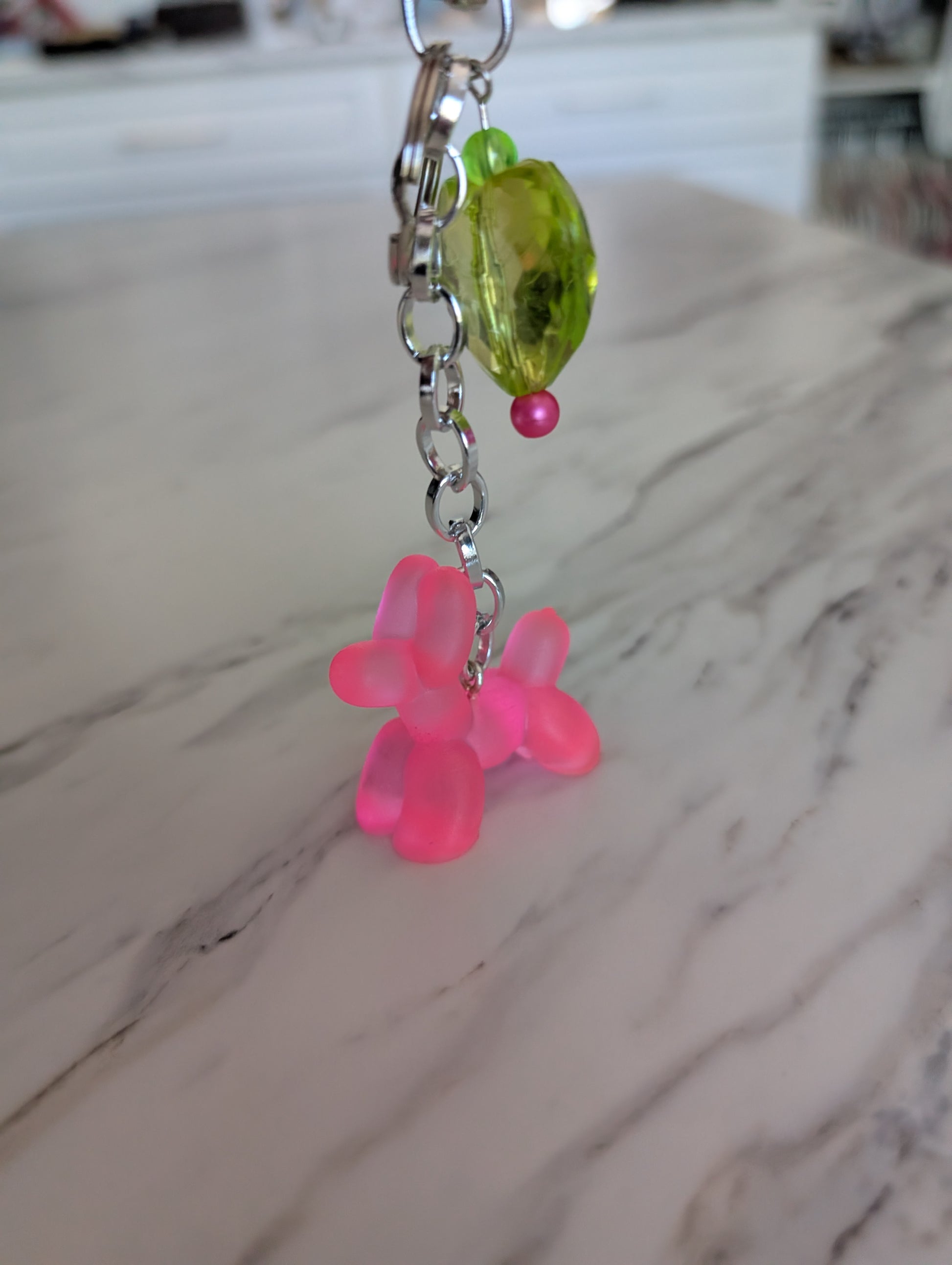Keychain with pink flower-shaped charms and green and pink beads on a marble surface