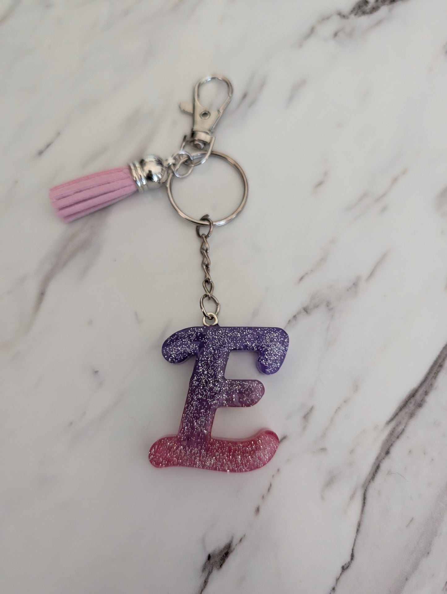 Keychain with letter 'E' and tassel on a marble background