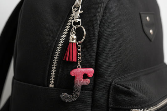 Keychain with letter 'F' and tassel attached to a black bag