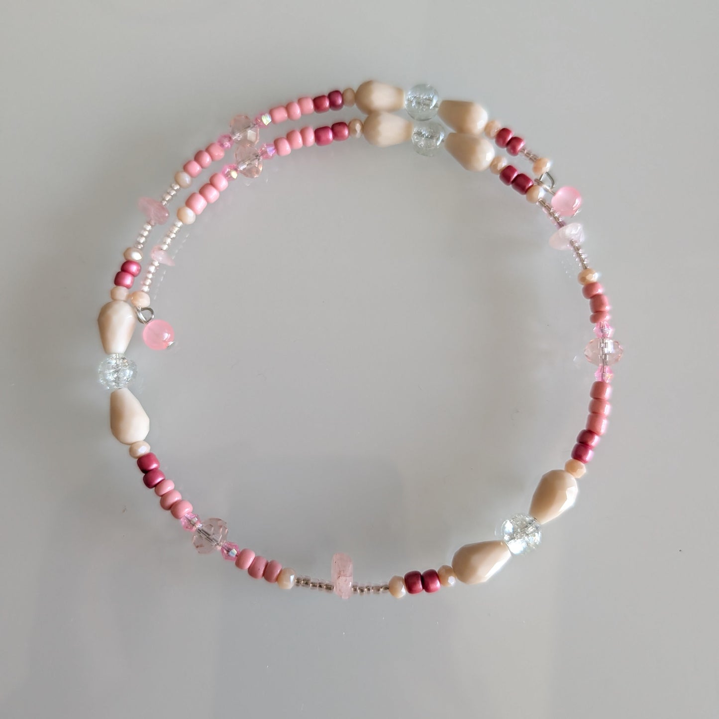 Artisan coil choker with a gradient of matte cream glass beads and rose-tinted crystals, designed without a clasp for a seamless look.