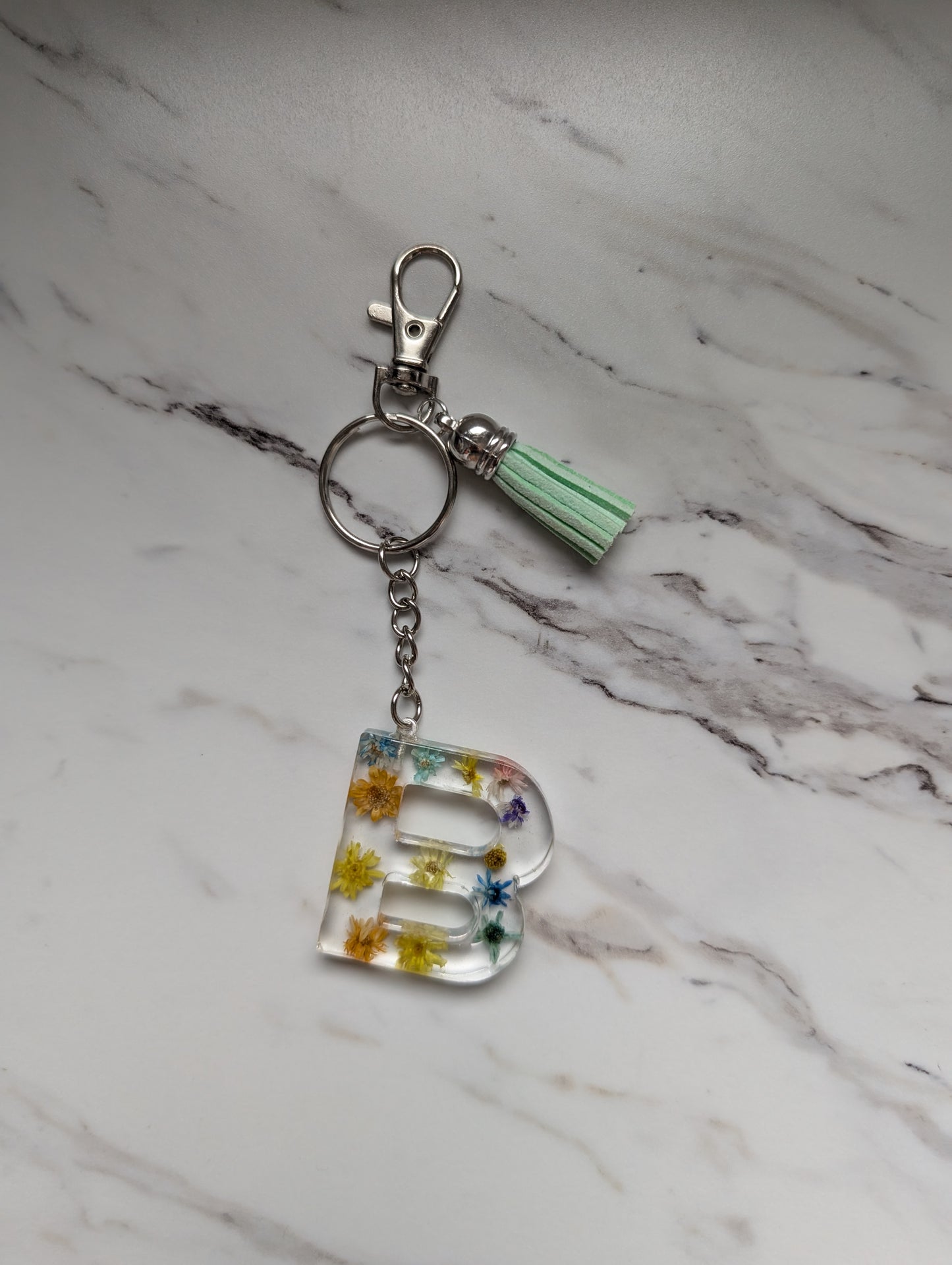 Keychain with floral letter 'B' charm on a marble surface