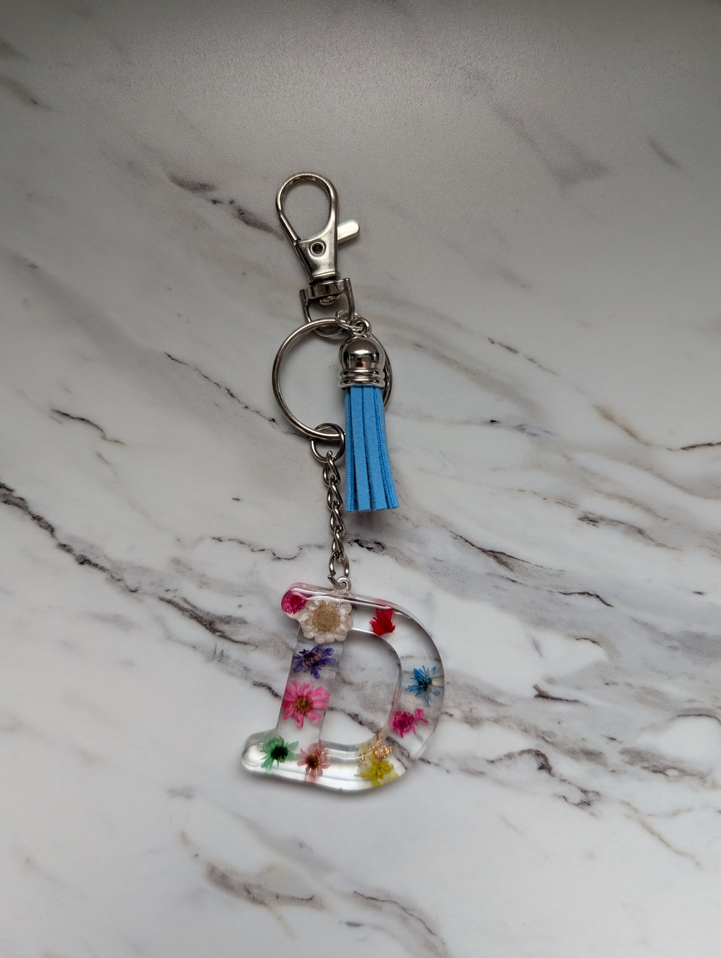 Keychain with colorful letter 'D' design on a marble surface